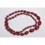 A GRADUATED CHERRY AMBER COLOUR BEADED NECKLACE, fifty-two graduated oval beads, individually