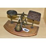 A SET OF POSTAL WEIGHING SCALES WITH A SET OF FIVE WEIGHTS, the gilt metal frame is mounted to a