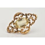 A LATE VICTORIAN GOLD CITRINE BROOCH, the central oval citrine within a scrolling openwork surround,