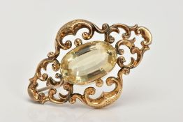A LATE VICTORIAN GOLD CITRINE BROOCH, the central oval citrine within a scrolling openwork surround,
