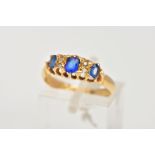 AN EARLY 20TH CENTURY BOAT RING, designed with three oval cut blue stones assessed as garnet and