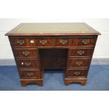 A MAHOGANY KNEE HOLE DESK, the top with a green tooled leather inlay, eight various drawers,