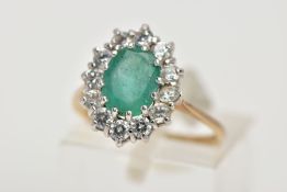 A 9CT GOLD EMERALD AND CUBIC ZIRCONIA CLUSTER RING, designed with a central oval cut emerald, within