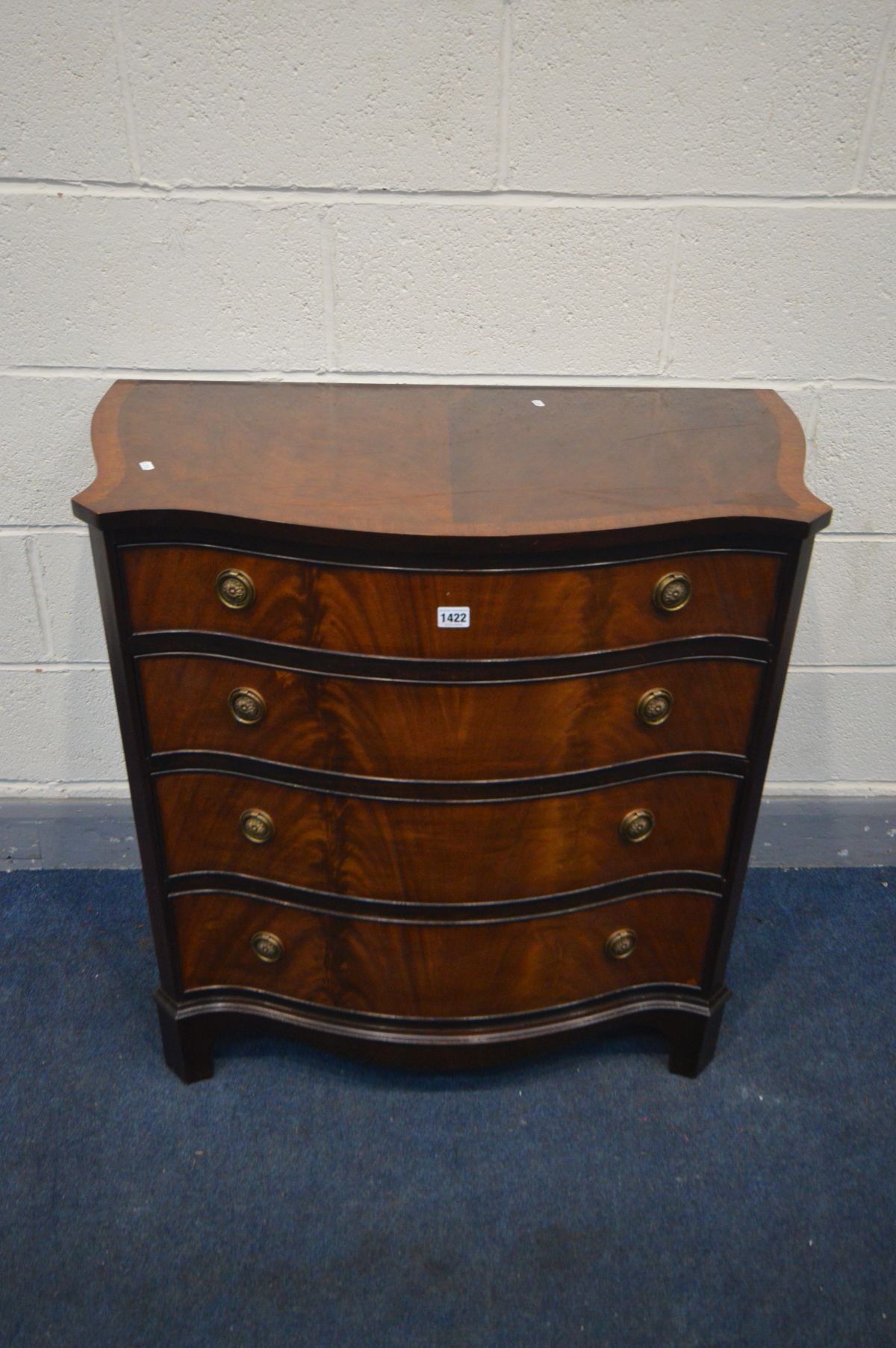 A REPRODUCTION MAHOGANY AND CROSSBANDED SERPENTINE CHEST OF FOUR LONG GRADUATED DRAWERS, on