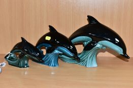 THREE POOLE POTTERY DOLPHIN FIGURES, graduated in size from heights 18cm to 11cm, the coloured