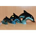 THREE POOLE POTTERY DOLPHIN FIGURES, graduated in size from heights 18cm to 11cm, the coloured