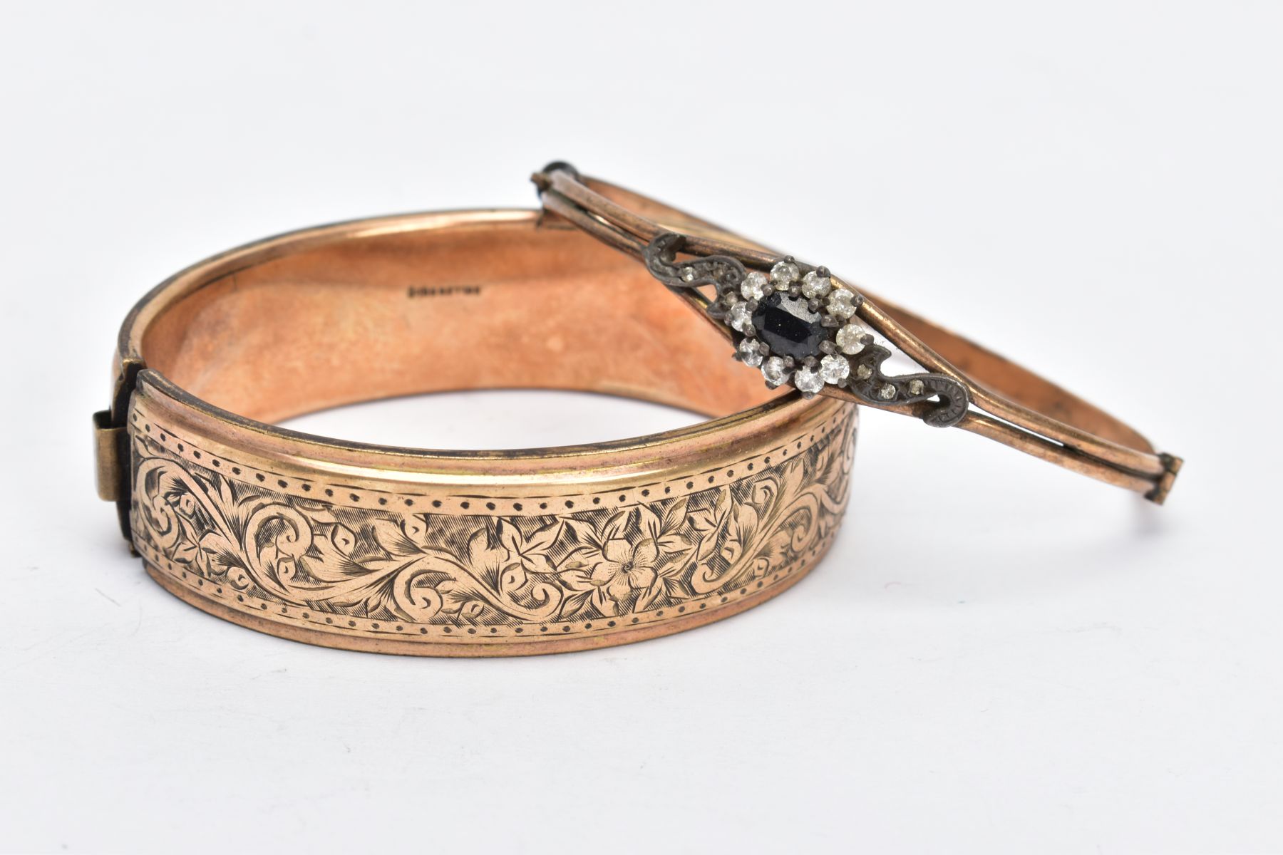 TWO ROLLED GOLD BANGLES, the first a wide bangle, decorated with an engraved floral design, fitted