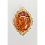A 9CT GOLD AMBER PENDANT, large oval amber cabochon, collet mounted within a decorative foliate