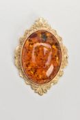 A 9CT GOLD AMBER PENDANT, large oval amber cabochon, collet mounted within a decorative foliate