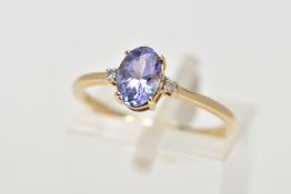 A 9CT GOLD TANZANITE AND DIAMOND RING, designed with a four claw set, oval cut tanzanite, flanked