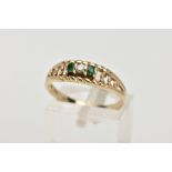A 9CT GOLD DIAMOND AND EMERALD RING, designed with a central round brilliant cut diamond, flanked