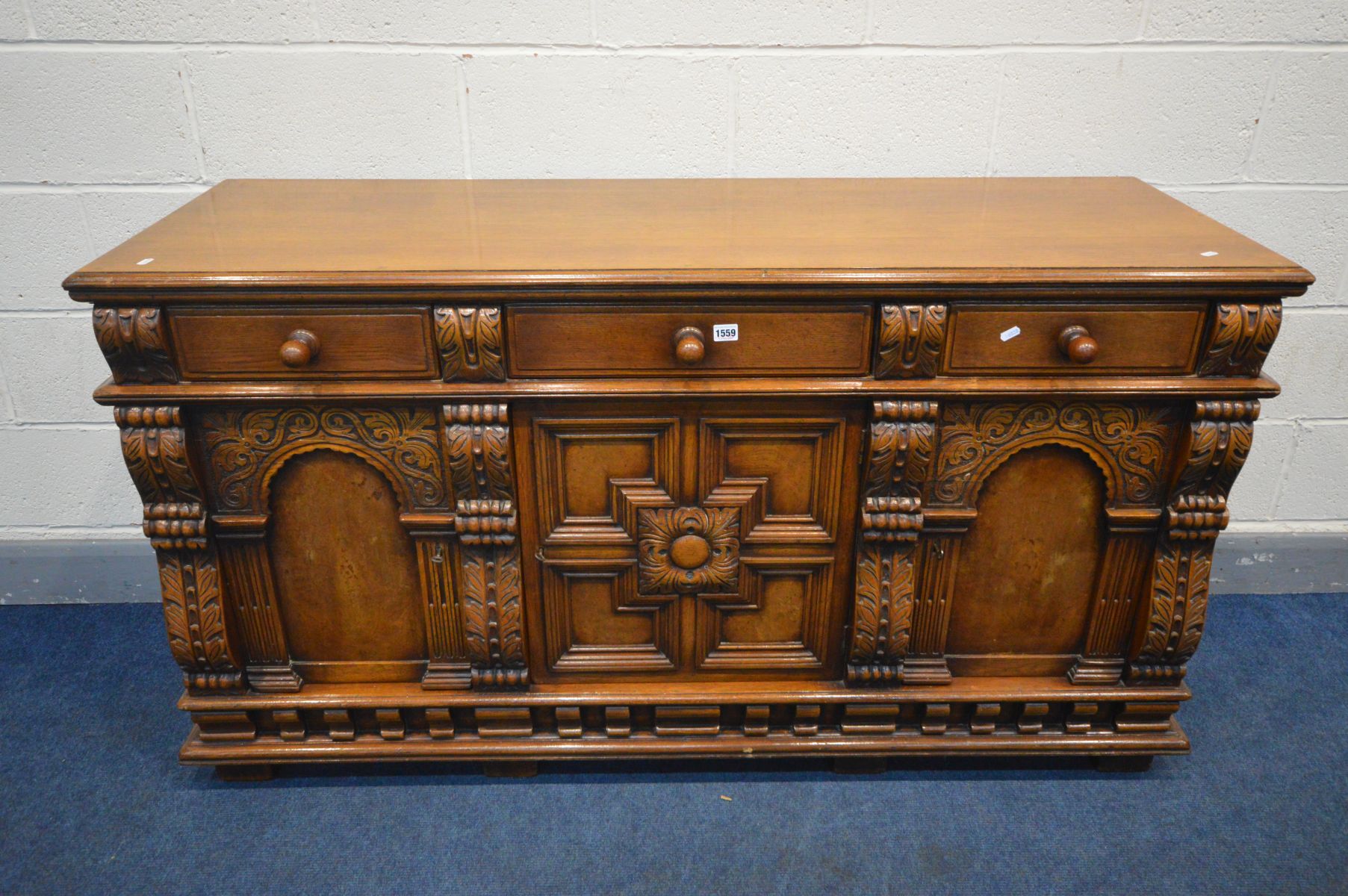 A REPRODUCTION SOLID OAK SIDEBOARD, with three drawers above two arched panelled doors flanking a