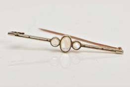 AN EARLY 20TH CENTURY MOONSTONE BAR BROOCH, set with a central oval moonstone cabochon, flanked by