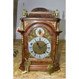 AN EARLY 20TH CENTURY WALNUT AND GILT METAL QUARTER STRIKING BRACKET CLOCK, the carved dome