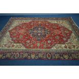 A WOOLLEN ISFAHAN CARPET, the red field centred by a blue medallion, framed by a multi strap border,