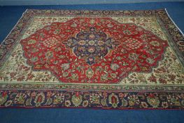 A WOOLLEN ISFAHAN CARPET, the red field centred by a blue medallion, framed by a multi strap border,