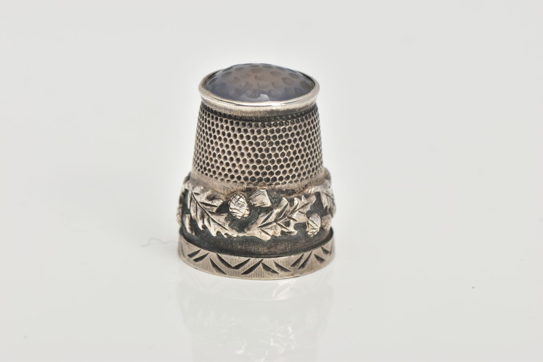 A SILVER THIMBLE, decorated with thistles and set with a possibly chalcedony terminal, hallmarked '