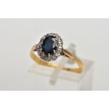 AN 18CT GOLD SAPPHIRE AND DIAMOND CLUSTER RING, designed with an oval cut blue sapphire within a