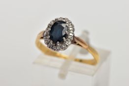 AN 18CT GOLD SAPPHIRE AND DIAMOND CLUSTER RING, designed with an oval cut blue sapphire within a