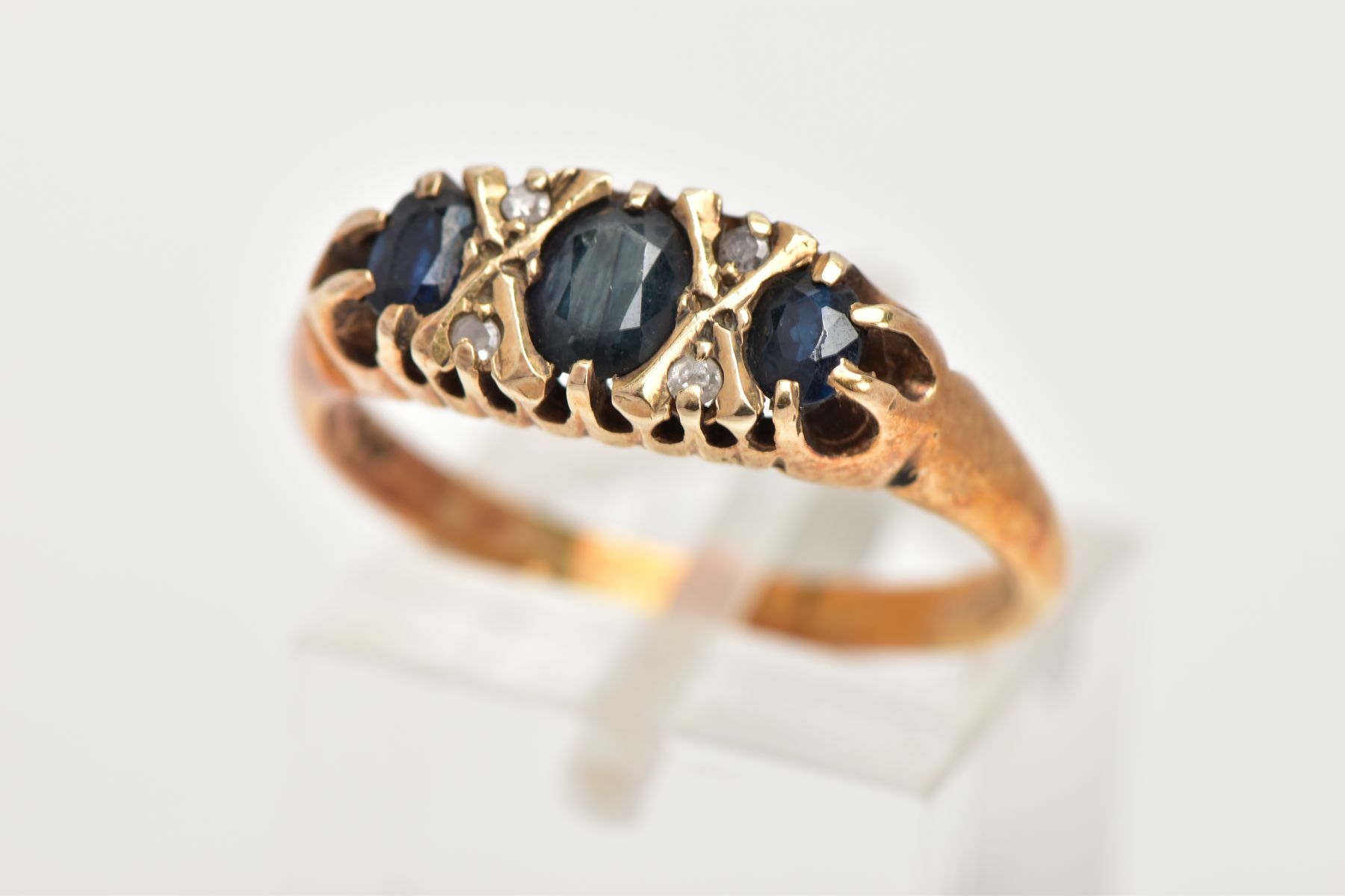 A 9CT GOLD SAPPHIRE AND DIAMOND RING, designed with three graduated oval cut blue sapphires,