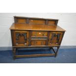 AN EDWARDIAN OAK SIDEBOARD with a raised back, two doors flanking two drawers with brass handles,