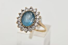 A 9CT GOLD TOPAZ CLUSTER RING, designed with a central oval cut blue topaz, within a surround of