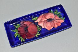 A MOORCROFT POTTERY RECTANGULAR TRAY IN THE ANEMONE PATTERN ON A DARK BLUE GROUND, impressed marks