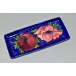 A MOORCROFT POTTERY RECTANGULAR TRAY IN THE ANEMONE PATTERN ON A DARK BLUE GROUND, impressed marks