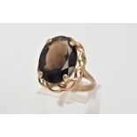 A 9CT GOLD LARGE SMOKEY QUARTZ DRESS RING, centring on a four claw set, oval cut Smokey quartz