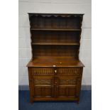 A REPRODUCTION OAK DRESSER with two drawers above two carved and fielded cupboard doors, width 107cm