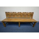 AN REPRODUCTION OAK SETTLE/PEW, with seven shaped panels to the back, length 203cm