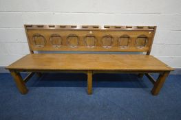 AN REPRODUCTION OAK SETTLE/PEW, with seven shaped panels to the back, length 203cm