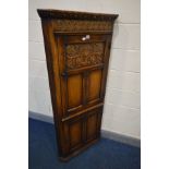A REPRODUCTION SOLID OAK CORNER CUPBOARD with carved and panelled doors and later shelves, width