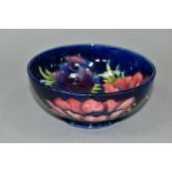 A MOORCROFT POTTERY FOOTED BOWL DECORATED WITH ANEMONES ON A DARK BLUE GROUND, impressed and painted