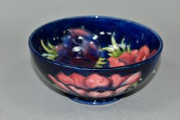 A MOORCROFT POTTERY FOOTED BOWL DECORATED WITH ANEMONES ON A DARK BLUE GROUND, impressed and painted