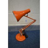 AN ORANGE ANGLE POISE DESK LAMP