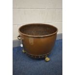 A RIVETED COPPER LOG BIN, with twin brass handles, on triple lions pad feet, diameter 51cm x