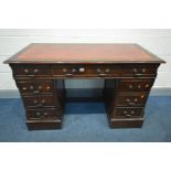 A MAHOGANY PEDESTAL DESK, with oxblood and gilt tooled leather inlayed top and seven assorted