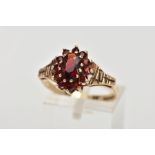 A 9CT GOLD GARNET CLUSTER RING, designed with a central oval cut garnet, within a surround of