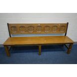 AN REPRODUCTION OAK SETTLE/PEW, with seven shaped panels to the back, length 203cm