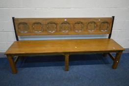 AN REPRODUCTION OAK SETTLE/PEW, with seven shaped panels to the back, length 203cm