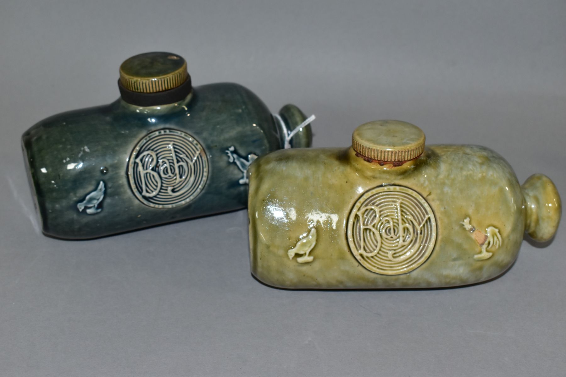 TWO ROYAL DOULTON STONEWARE 'BABY' HOT WATER BOTTLES, from nursery ware series, c.1910, both with