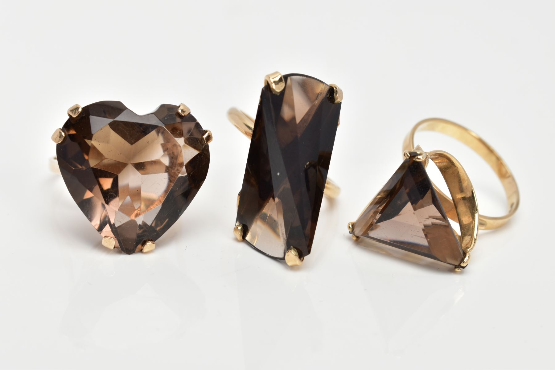 THREE 9CT GOLD SMOKEY QUARTZ DRESS RINGS, the first designed with a heart shaped Smokey quartz,