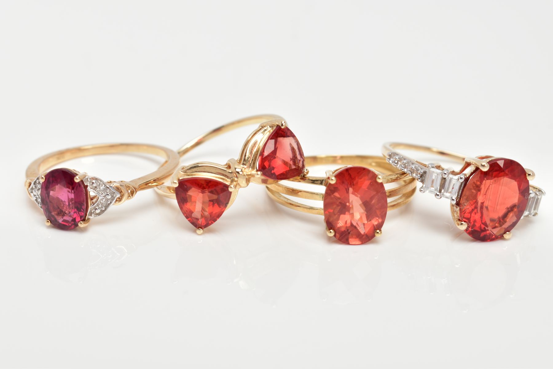 FOUR 9CT GOLD GEM SET RINGS, each set with orangish red stones, assessed as garnet and Oregan