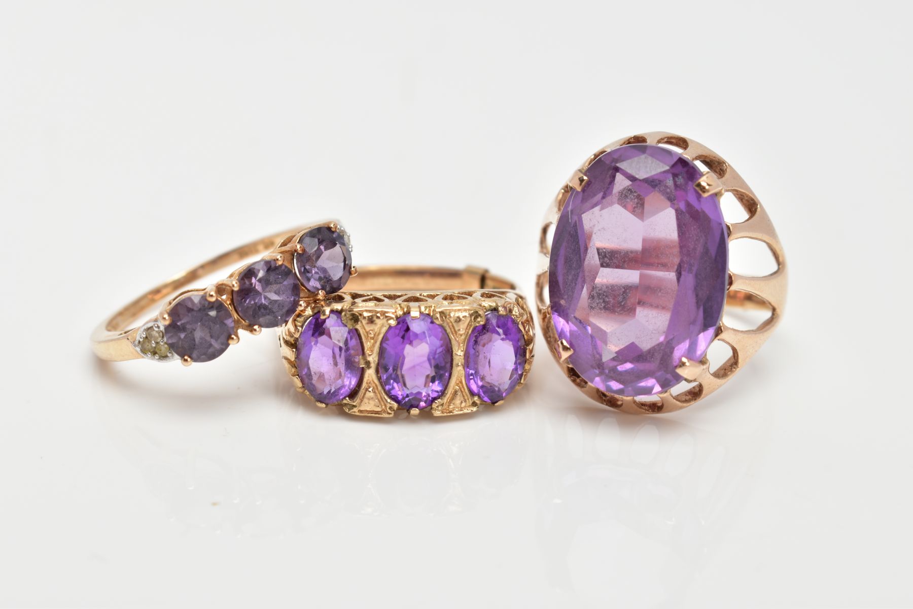 THREE 9CT GOLD AMETHYST DRESS RINGS, a large oval cut amethyst, ring size O, a three stone