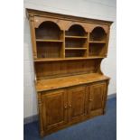 A PINE DRESSER, the top with open shelving, above a base with three fielded panel cupboard doors,