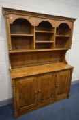 A PINE DRESSER, the top with open shelving, above a base with three fielded panel cupboard doors,