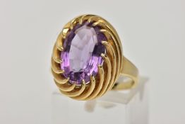 A YELLOW METAL AMETHYST DRESS RING, designed with a claw set, oval cut amethyst, measuring