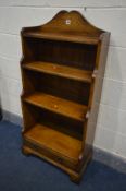 A REPRODUCTION OAK WATERFALL OPEN BOOKCASE, with a raised top, four shelves above a single long