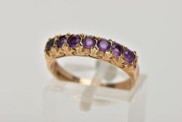 A 9CT GOLD AMETHYST HALF ETERNITY RING, designed with a row of seven circular cut amethysts,